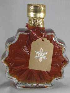 Snowflake shaped glass bottle filled with natural maple syrup with gift tag 